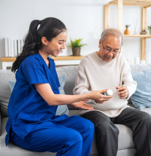 caregiver giving medicine to elderly man