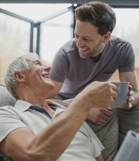 male caregiver giving a cup of coffee to the senior man