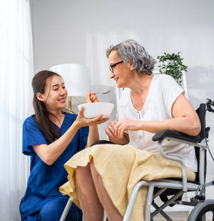 caregiver feeding elderly woman