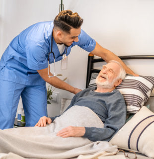 caregiver taking care of elderly man in bed