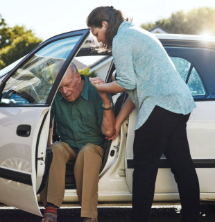 caregivers helping elderly in the car